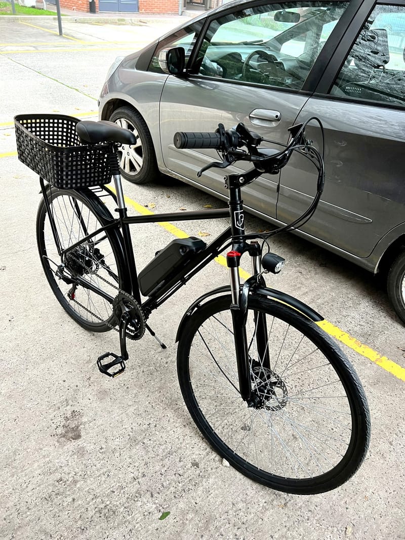 Bicicleta eléctrica Frank negra rodado 28 con batería de litio en el cuadro, canasto trasero y luz delantera, en Vicente López